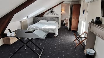 Een kleine kamer met een bed, een tafeltje, een stoel, een radiator en een kledingkast.