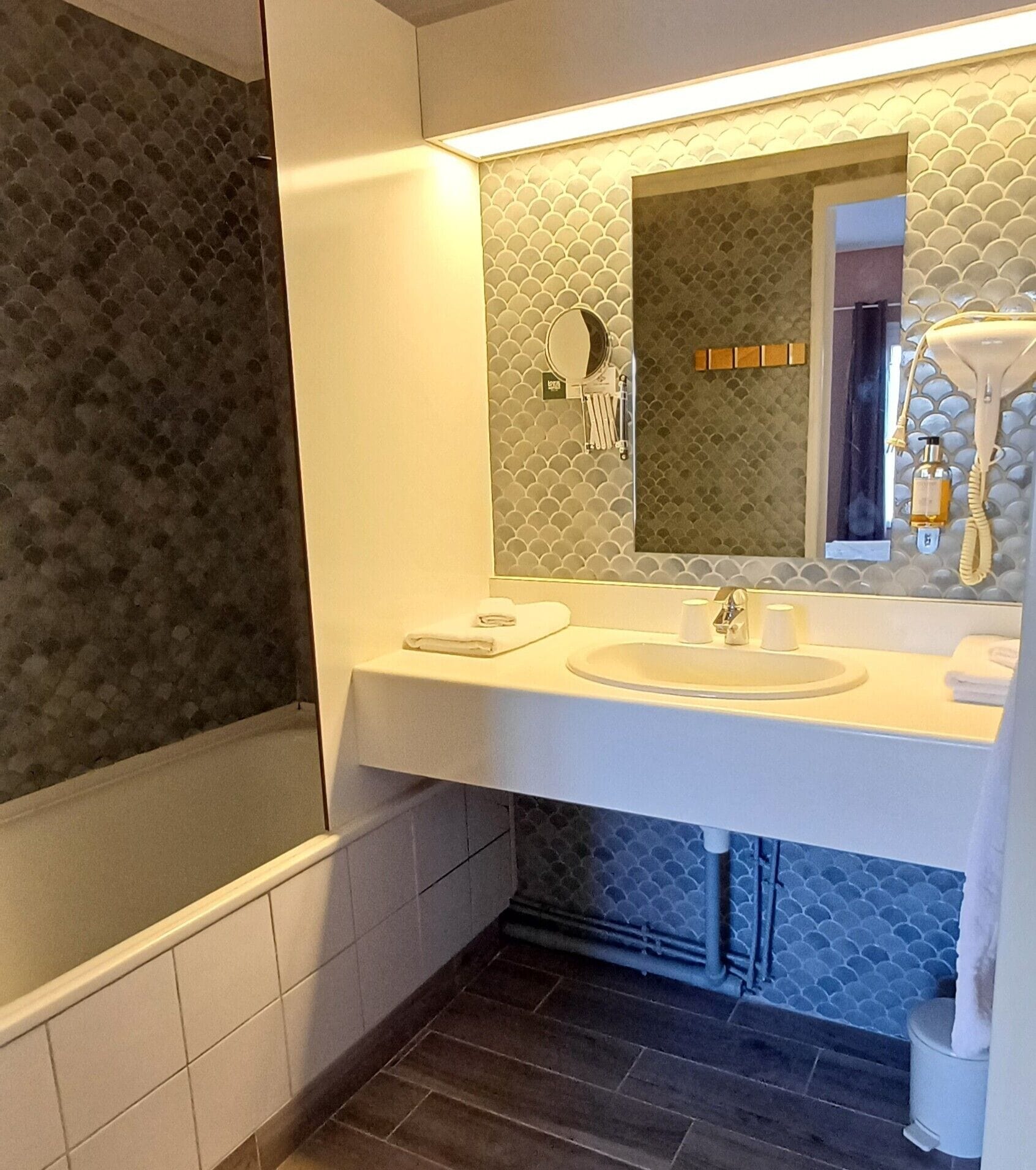 A modern bathroom with a bathtub, a sink, and a mirror.
