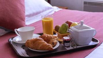 Een ontbijfwagen met croissants, een glas sinaasappelsap, een kop, een karaf en een kleine schaal fruit op een bed met roze beddengoed.