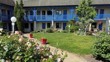 A hotel with a blue and white exterior, a well-maintained lawn, and potted plants.