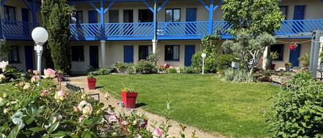 A hotel with a blue and white exterior, a well-maintained lawn, and potted plants.