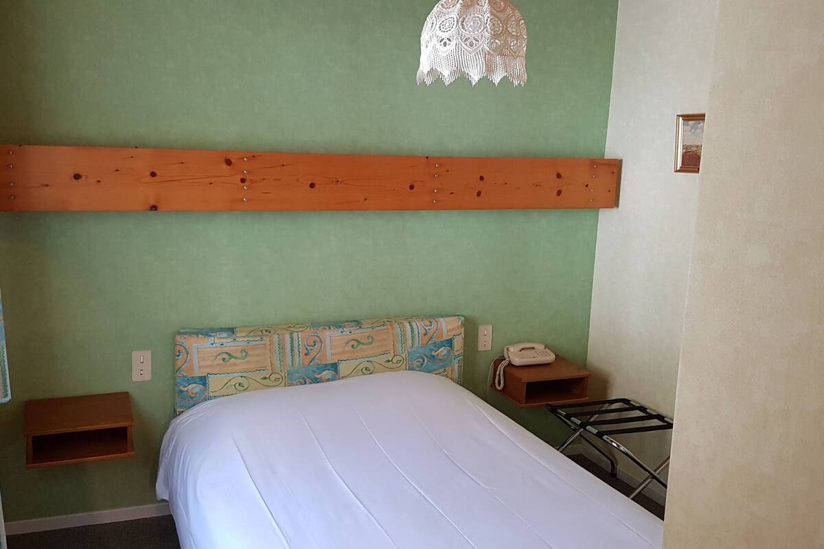 Ein Schlafzimmer mit Bett, Nachttisch, Telefon und Wandregal.