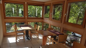 Un comedor con ventanas amplias, mobiliario de madera y vistas al exterior.