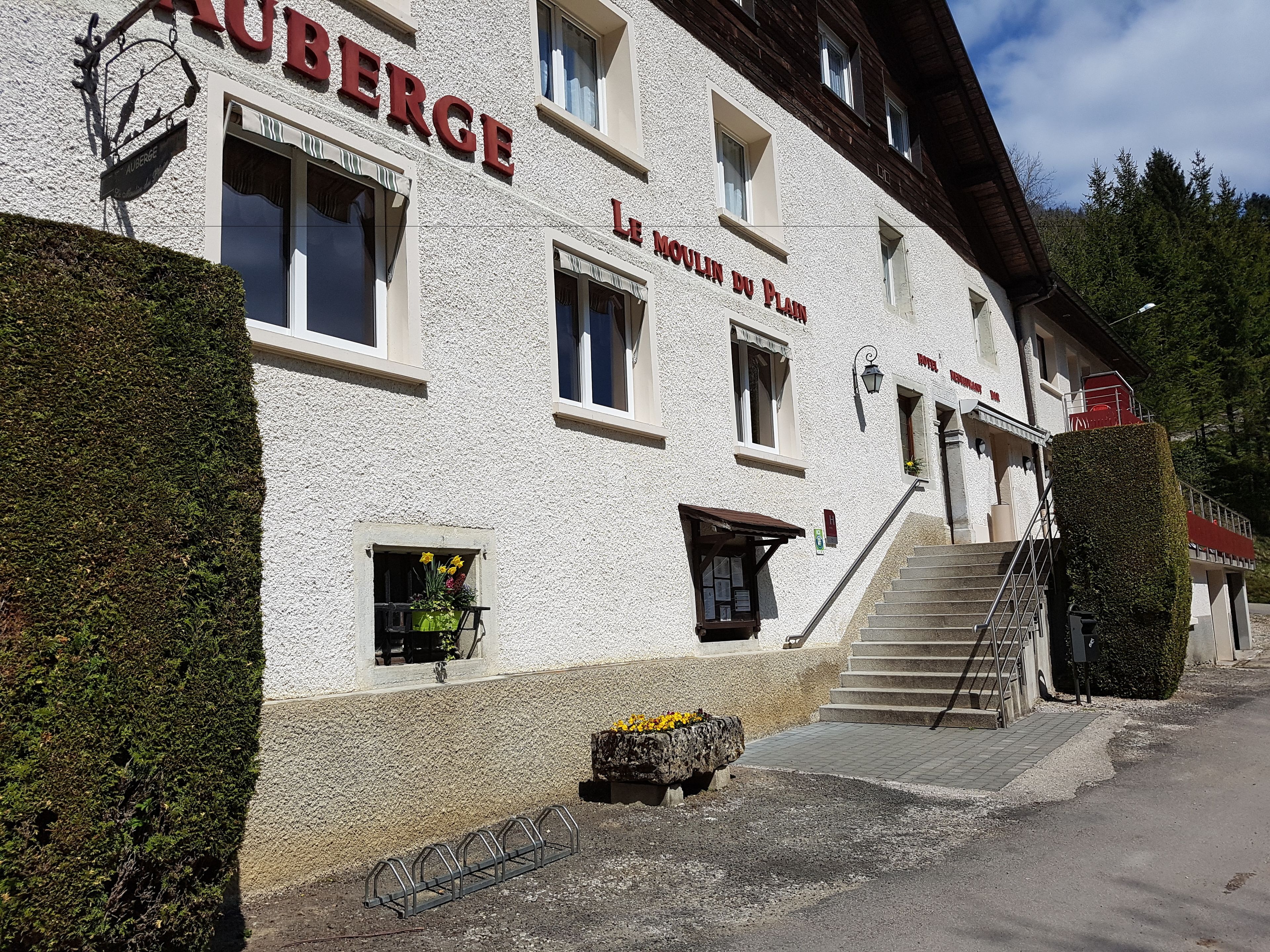 A building with a sign reading "Le Moulin du Plain" and a staircase leading to the entrance.