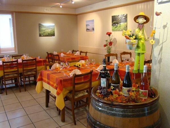 Un restaurante con mesas preparadas para comer, una figura decorativa sobre un barril y cuadros en la pared.