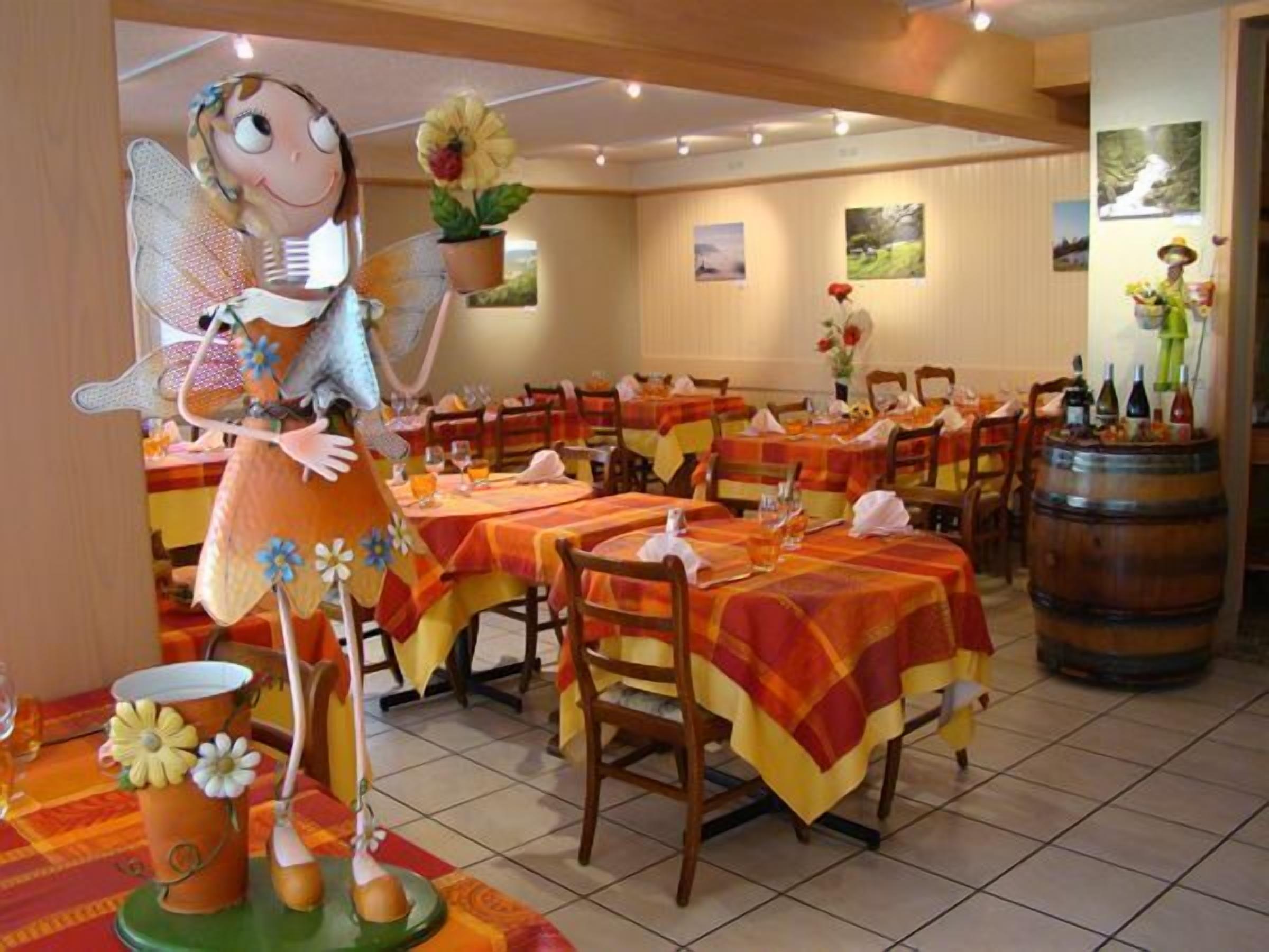 A restaurant with multiple tables, chairs, and a decorative fairy figure.