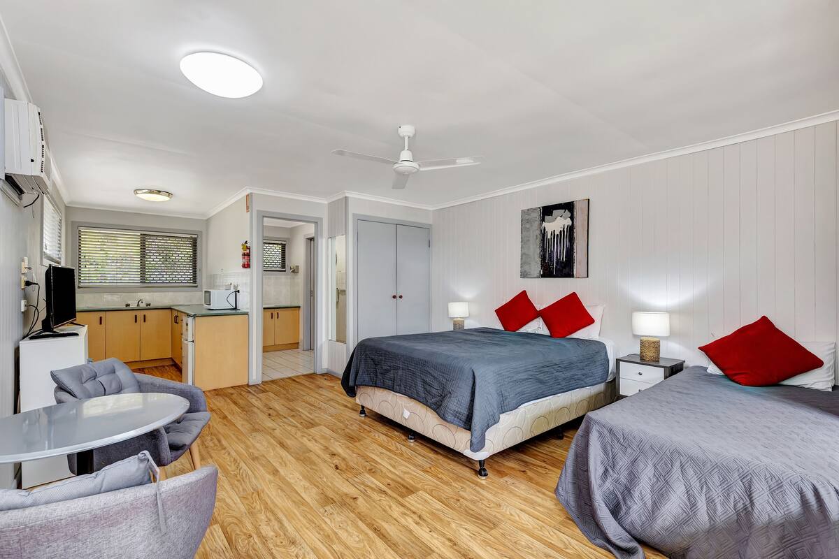 Un dormitorio con dos camas, una mesa de comedor y una kitchenette.