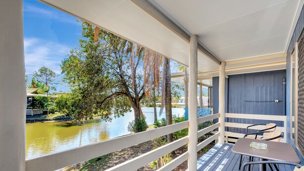 A covered outdoor area with a table and chairs, overlooking a body of water and trees. - Sanctuary Lakes Fauna Retreat (Urangan)