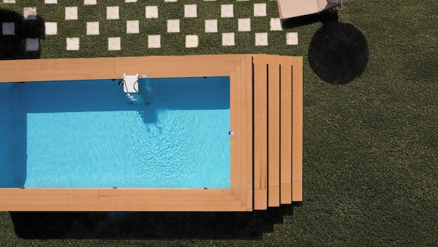 A rectangular pool with a wooden deck and a checkered lawn area. - Erifili Apartments (Corfu)