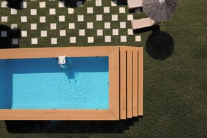 Una piscina rectangular con cubierta de madera y césped a cuadros.