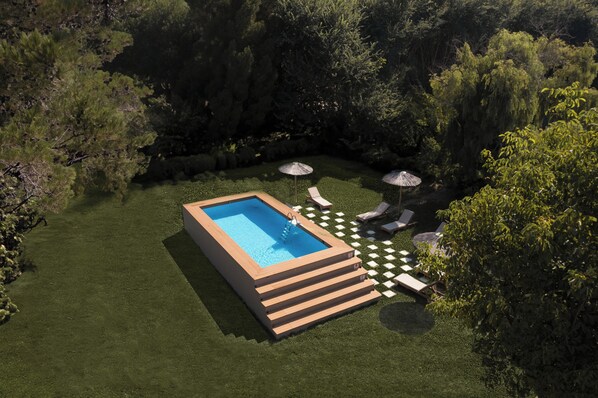Una piscina rectangular con cubierta de madera, rodeada por un césped cuidado y árboles.