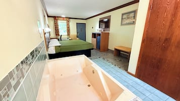 Una habitación con bañera, cama, escritorio y silla.
