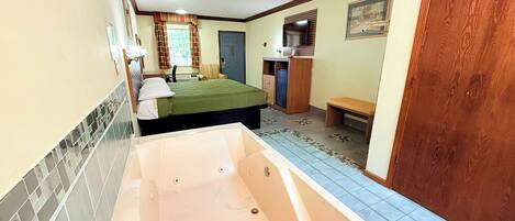Una habitación con bañera, cama, escritorio y silla.