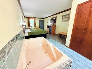 A room with a bathtub, a bed, a desk, and a chair. - Economy Inn - Akron (Cuyahoga Falls)
