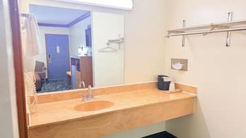 A bathroom with a wooden vanity, a sink, a mirror, and a towel rack.