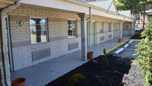 Un motel avec une rangée de chambres, chacune dotée d’une porte et d’une fenêtre.
