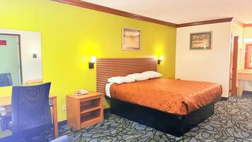 A hotel room with a bed, a chair, a nightstand, and a mirror.