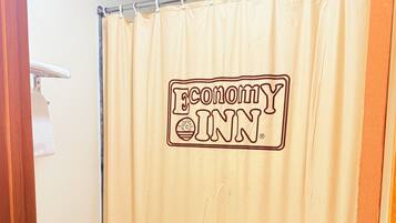 A bathroom with a shower curtain featuring a logo, a toilet, and a tiled floor.