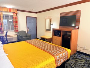 A hotel room with a bed, a desk, a chair, a television, and a microwave. - Economy Inn - Akron (Cuyahoga Falls)