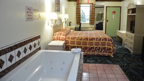 Une chambre d’hôtel comprenant un lit, un bureau, une chaise, une salle de bain avec baignoire et un téléviseur.