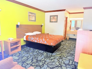 Une chambre d’hôtel comprenant un lit, une table de chevet et un bureau avec une chaise.