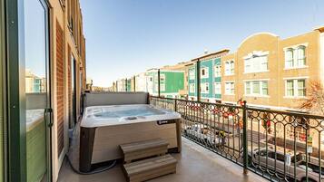 Un jacuzzi en un balcón con vistas a una hilera de casas de colores.