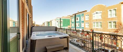 Un jacuzzi sur un balcon avec vue sur une rangée de maisons de ville aux couleurs vives.