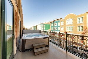 Un jacuzzi sur un balcon avec vue sur une rangée de maisons de ville aux couleurs vives.