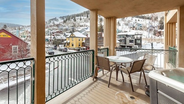 Een balkon met een jacuzzi, stoelen en een tafel.