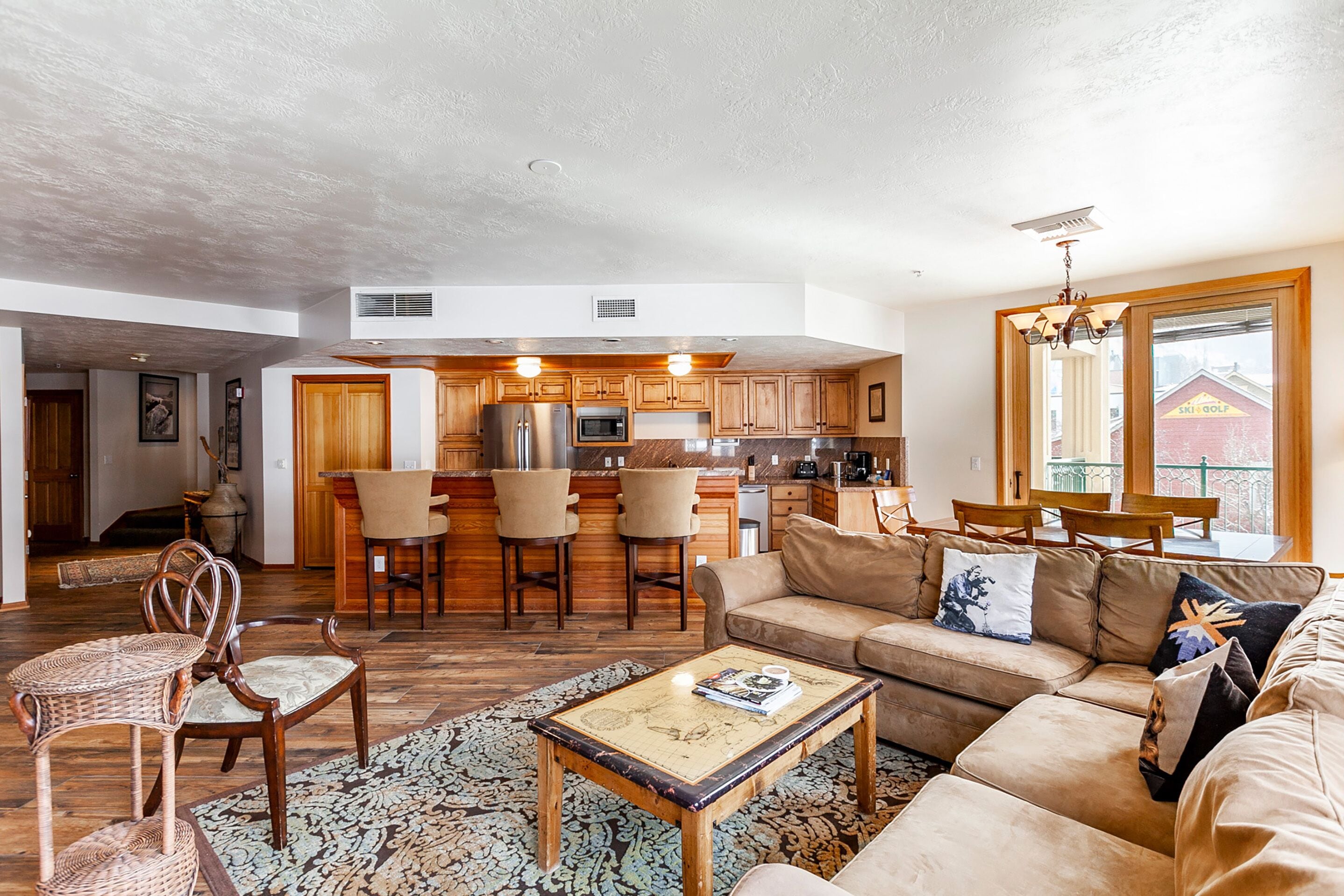 A spacious living area with a sofa, chairs, a coffee table, and a kitchen in the background.