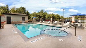 A swimming pool with a hot tub, lounge chairs, and a covered seating area.