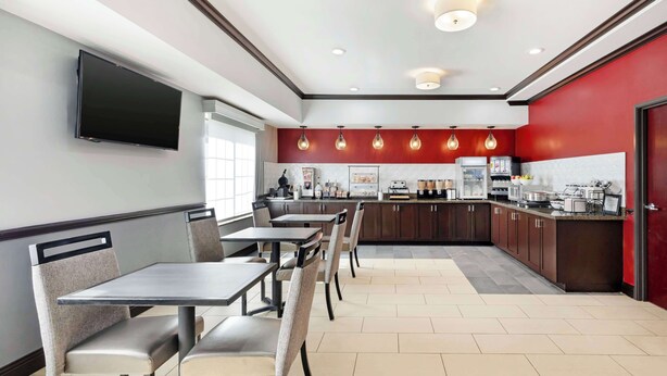A modern restaurant with a long counter, cushioned chairs, and a kitchen area in the background.
