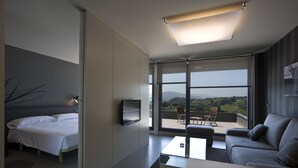 A modern hotel room with a bed, a sofa, a coffee table, and a TV mounted on the wall. -  FeelFree STAYS Basoa (San Sebastián)