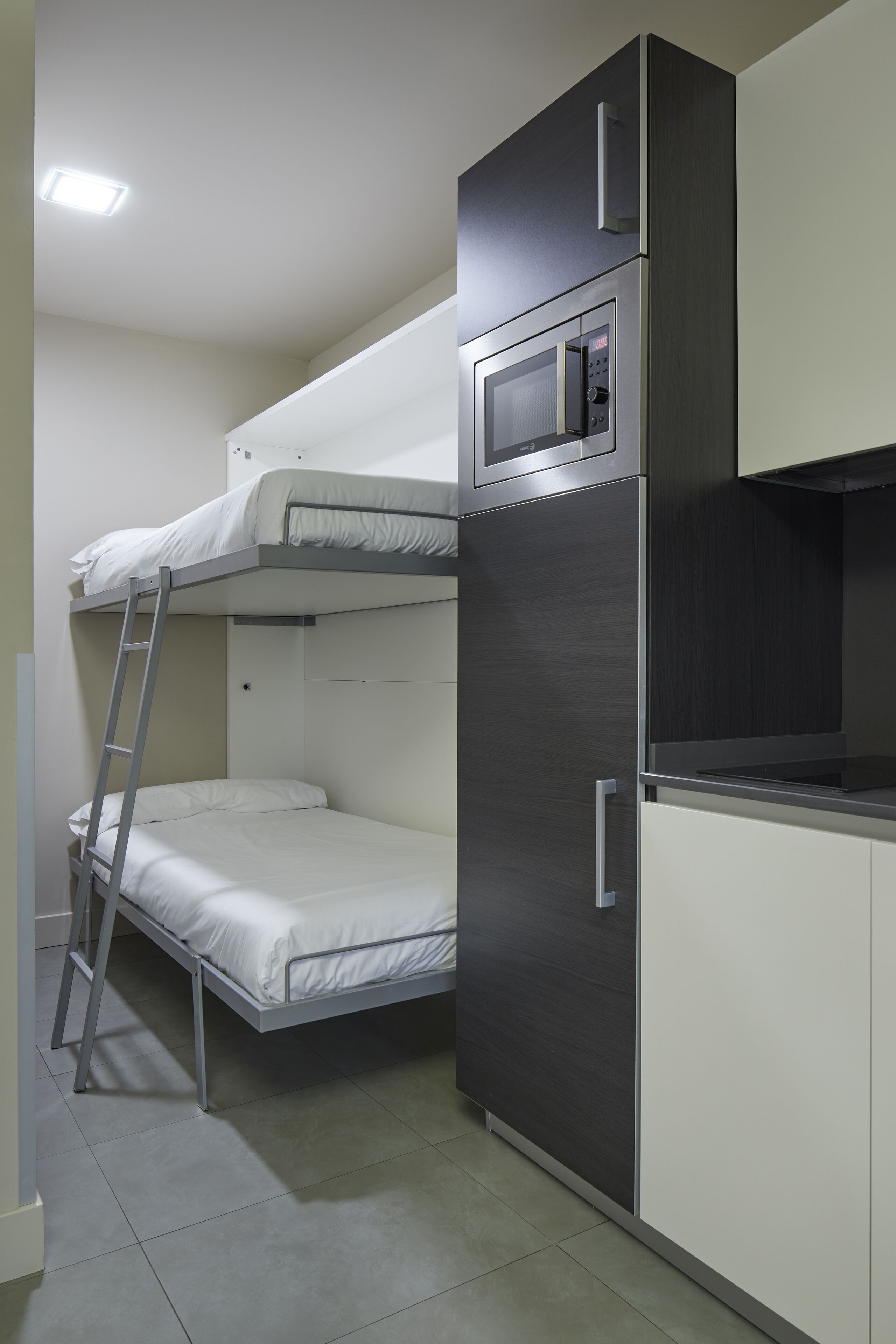 Una kitchenette compacta equipada con microondas, refrigerador y una litera.