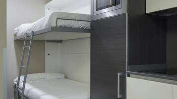 Una kitchenette compacta equipada con microondas, refrigerador y una litera.