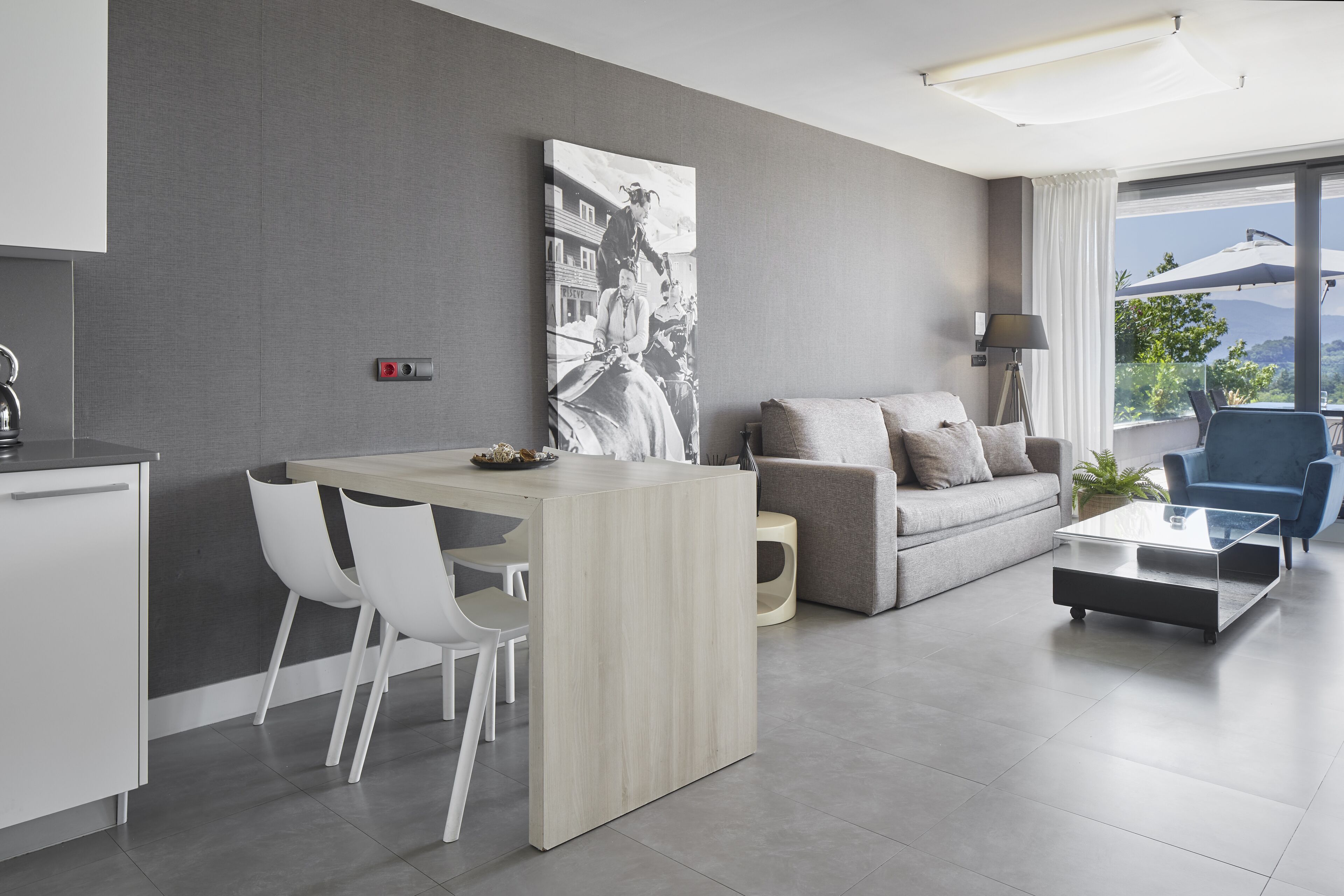 Una sala de estar moderna con sofá, mesa de centro y comedor con sillas.
