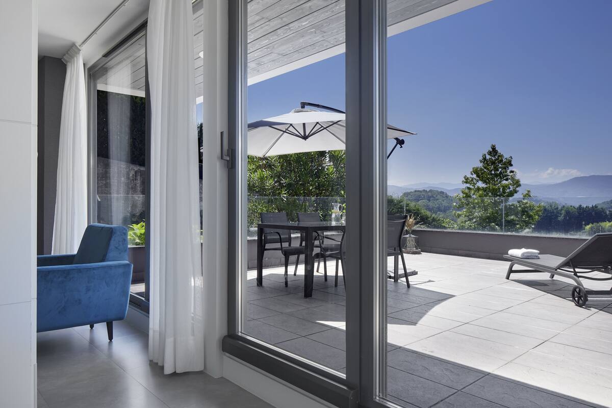 A modern balcony with a dining table, chairs, and a lounge chair.