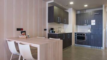 Una cocina moderna con armarios oscuros, una mesa de comedor de madera y sillas blancas.