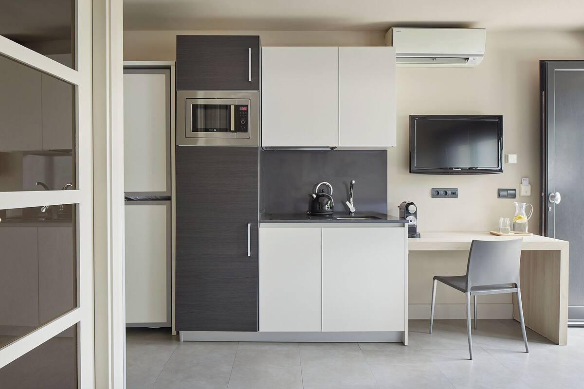 A compact kitchenette with a microwave, kettle, and sink.