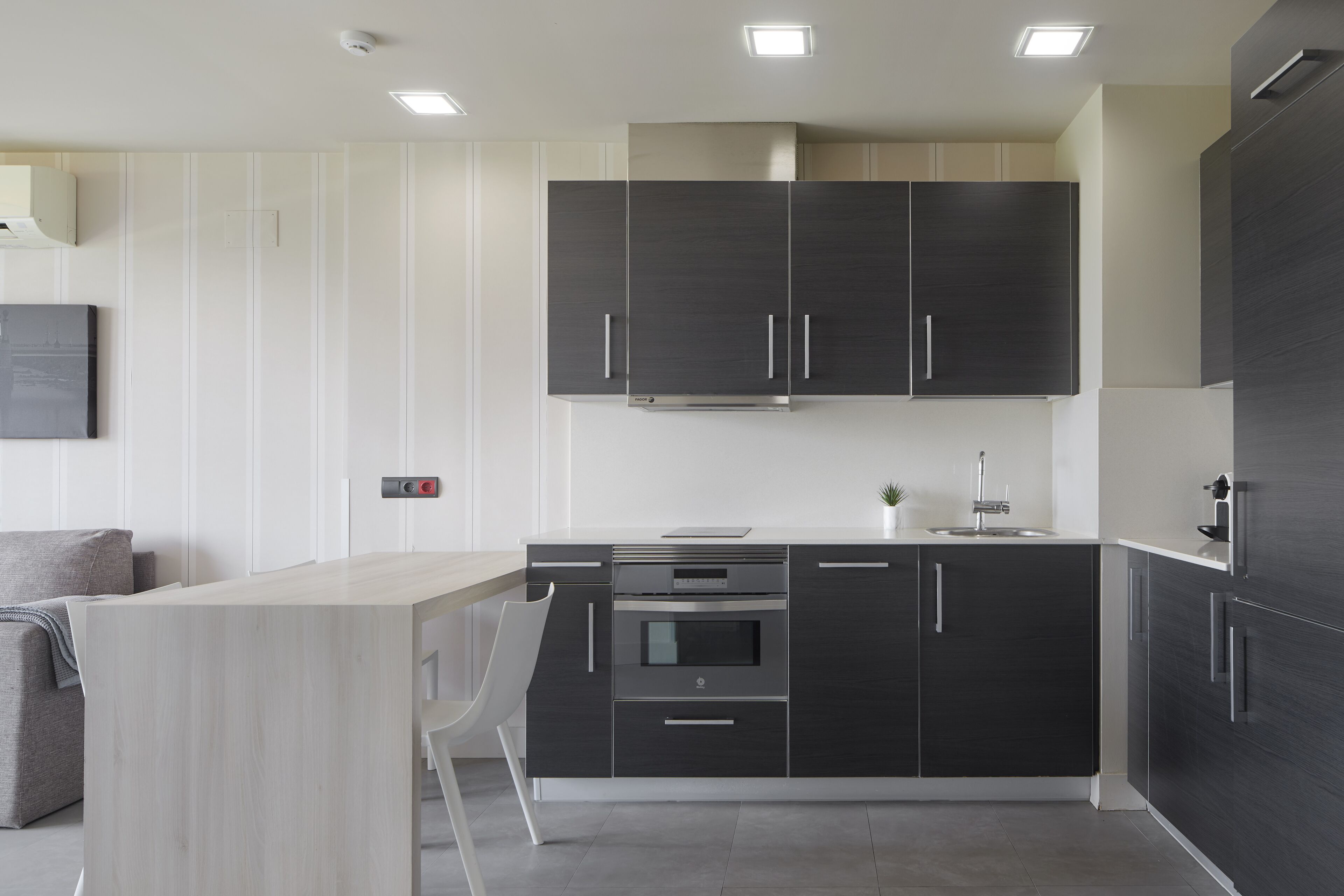Una cocina moderna con armarios oscuros, una encimera clara y un horno empotrado.
