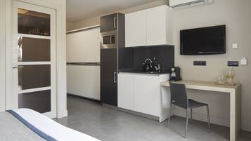 Una cucina moderna con forno a microonde, piano cottura e televisore a schermo piatto. C'è un'area pranzo con una sedia e un tavolo.