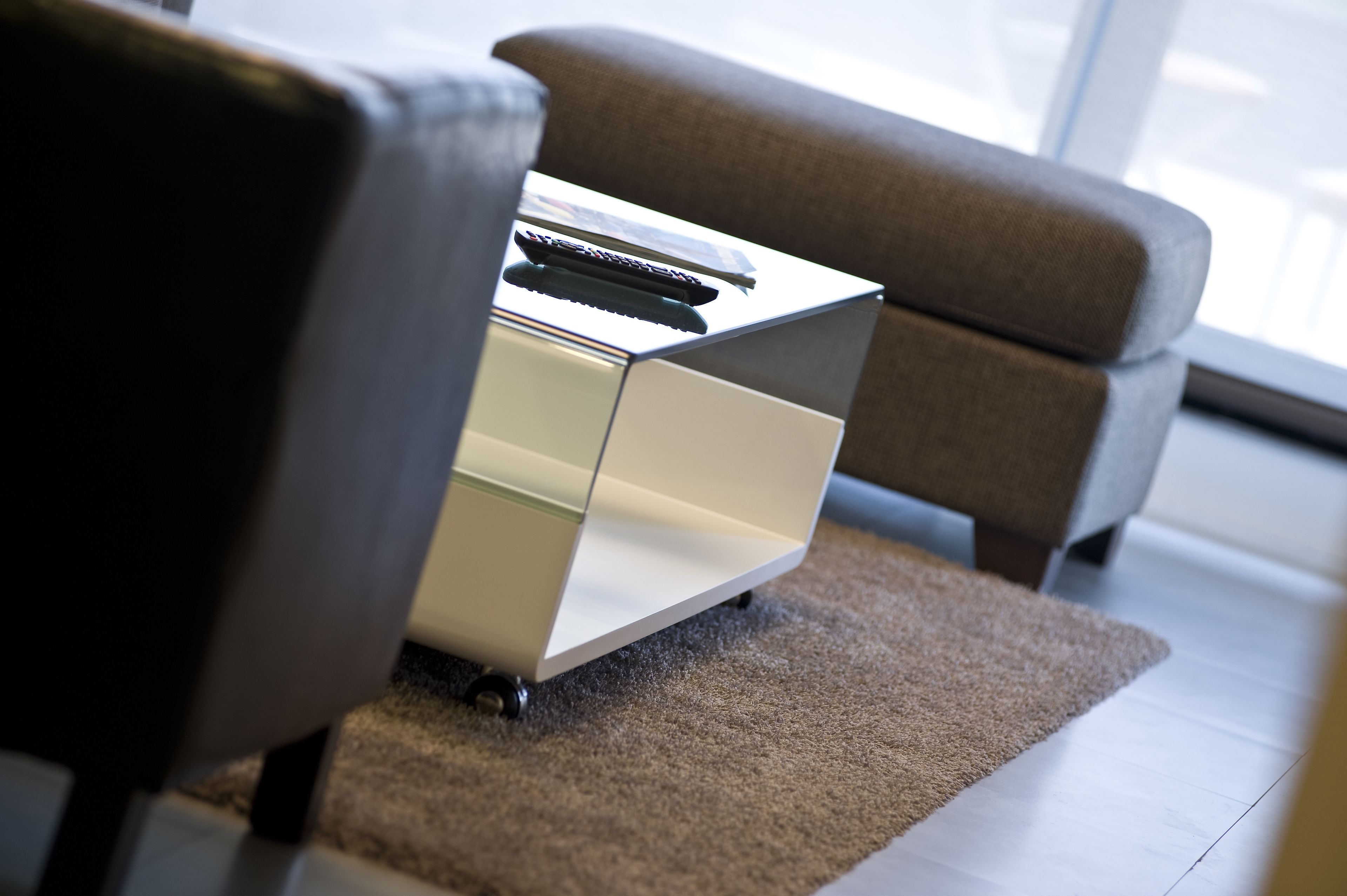 A modern, minimalist room with a sleek, metallic side table and a remote control on it.