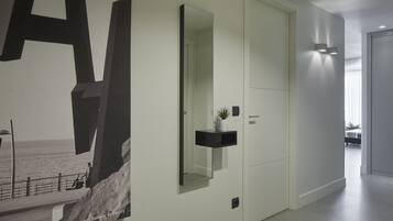A modern hallway with a large abstract art piece, a mirror, and a small plant on a shelf.