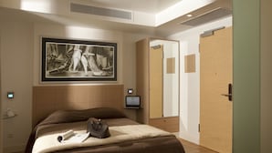 A modern hotel room with a large bed, a flat-screen TV, a wooden wardrobe, and a framed artwork on the wall. - Chic Hotel (Athens)