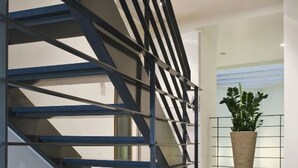 A modern staircase with a geometric design, leading to an interior space with a glass floor and a potted plant. - Chic Hotel (Athens)