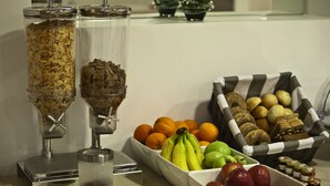 A breakfast buffet with granola, fruits, and bread. - Chic Hotel (Athens)