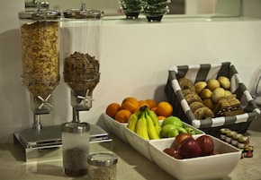 Um buffet de café da manhã com granola, frutas e pão.