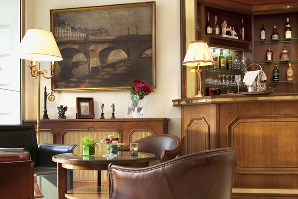 Un espace bar avec un comptoir en bois, des tabourets de bar et un tableau représentant un pont.