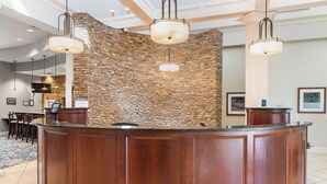 Un área de recepción con pared de piedra, mostrador de madera y lámparas colgantes.