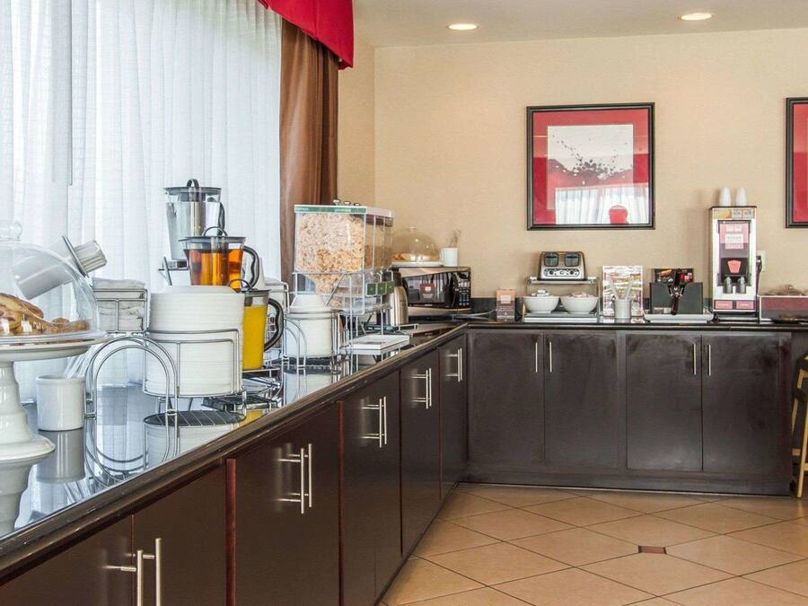 A modern kitchen with a breakfast bar, coffee machines, and a microwave.